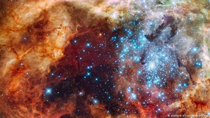 The massive, young stellar grouping, called R136, only a few million years old and residing in the 30 Doradus Nebula, a turbulent star-birth region in the Large Magellanic Cloud, a satellite galaxy of the Milky Way. 