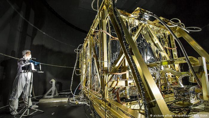 NASA photographer Desiree Stover (L), dressed in a clean room suit, shining a light on the Space Environment Simulator's Integration Frame inside the thermal vacuum chamber at NASA's Goddard Space Flight Center in Greenbelt, Maryland, USA, 29 August 2013. Shortly after, the chamber was closed up and engineers used this frame to enclose and help cryogenic (cold) test the heart of the James Webb Space Telescope, the Integrated Science Instrument Module. 