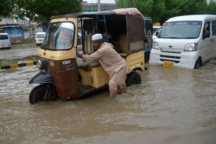 A man pushes his auto-rickshaw through a flooded street after heavy rains in Karachi on Tuesday.